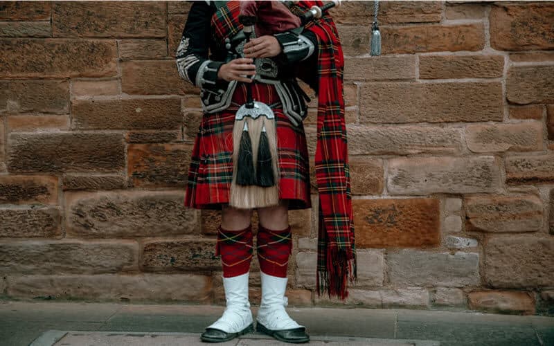 A Scotsman playing a bagpipe for visitors searching their Scottish ancestry