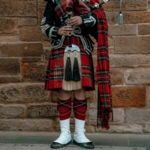 A Scotsman playing the bagpipes for visitors searching their Scottish ancestry.